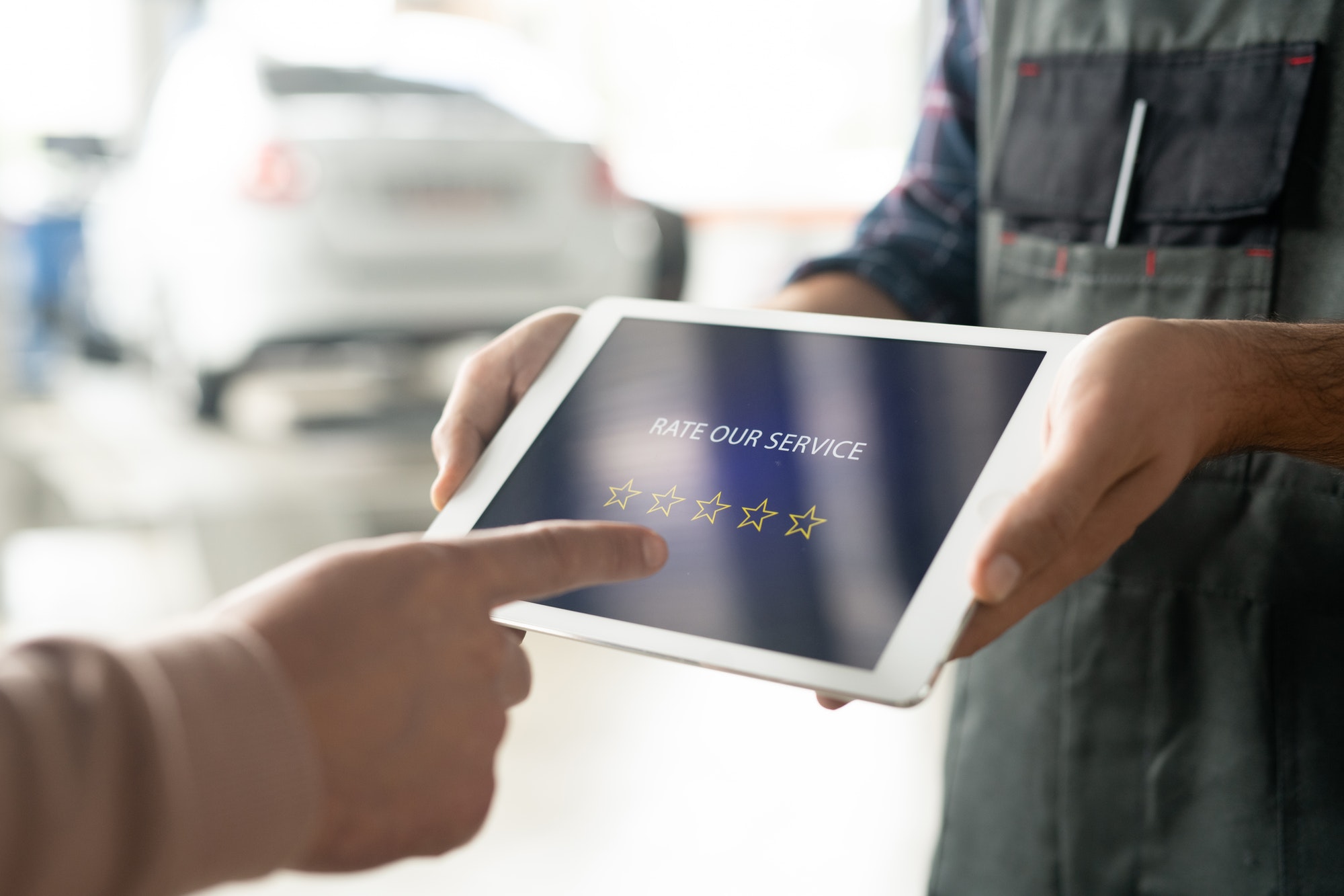 Car maintenance center technician holding tablet with five stars on display